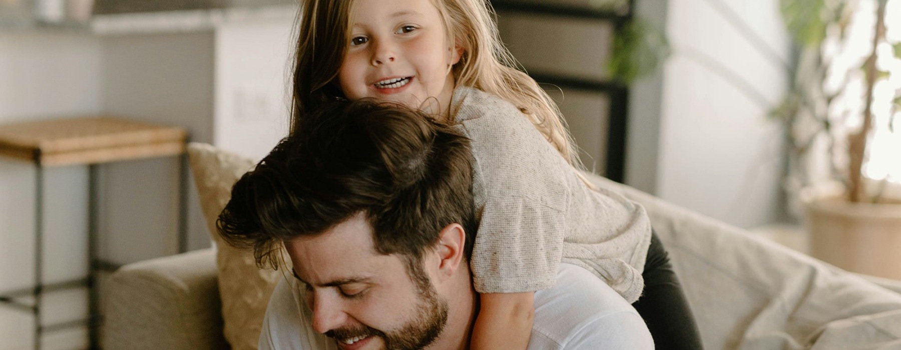 A girl hugging her father on a couch.